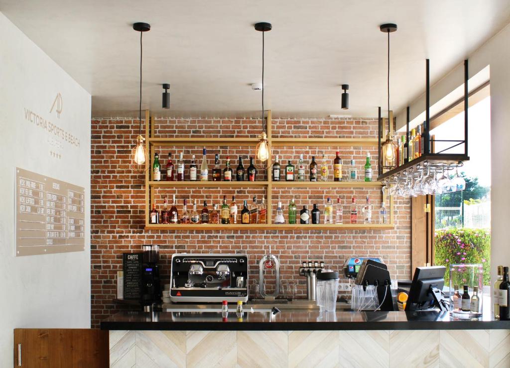 AP Victoria Sport & Beach Hotel modernais bārs ar ķieģeļu sienu un plašu dzērienu klāstu