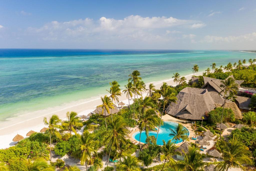 Zanzibar Queen piekrastes skats ar baseinu un palmu ieskautu vidi.