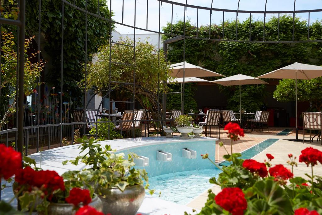 Dārzs ar baseinu un sarkaniem ziediem, kur var redzēt saulessargus un ēdiena galdiņus, piedāvā relaksējošu atmosfēru. Ideāla vieta atpūtai ārā.