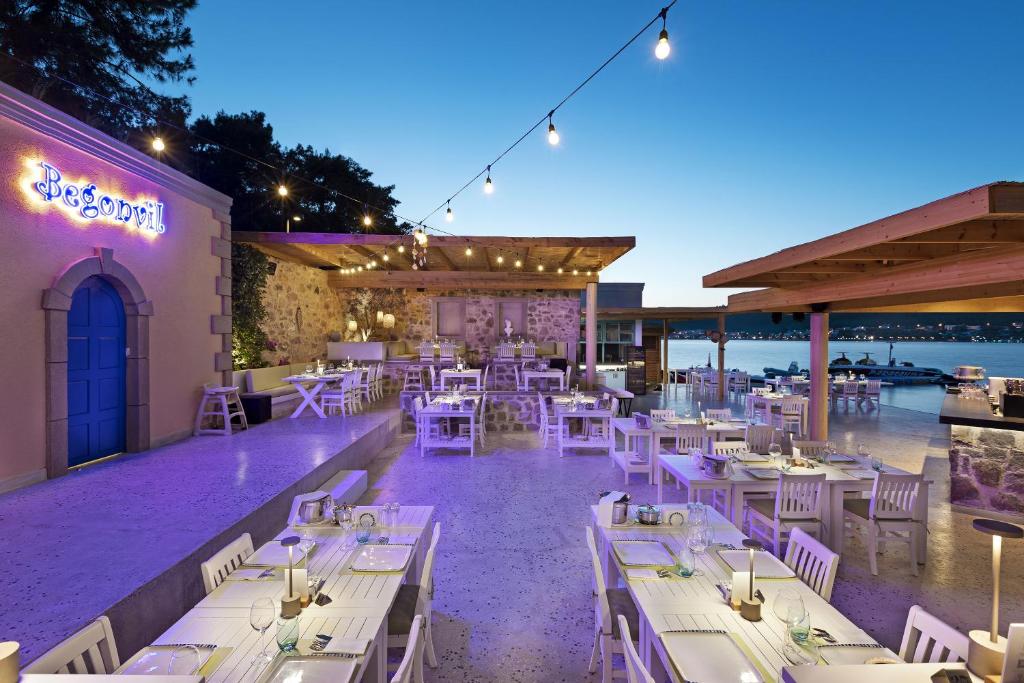 Āra restorāns Titanic Luxury Collection Bodrum ar elegantām galdiem un skatu uz jūru.