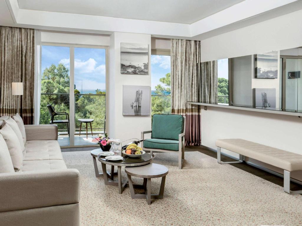 Rixos Premium Belek numurs ar modernu interjeru un skatu uz dabu.