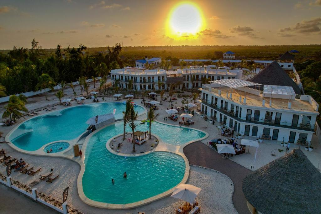 The One Resort Zanzibar piekrastē saulrietā ar baseinu un ēkām.