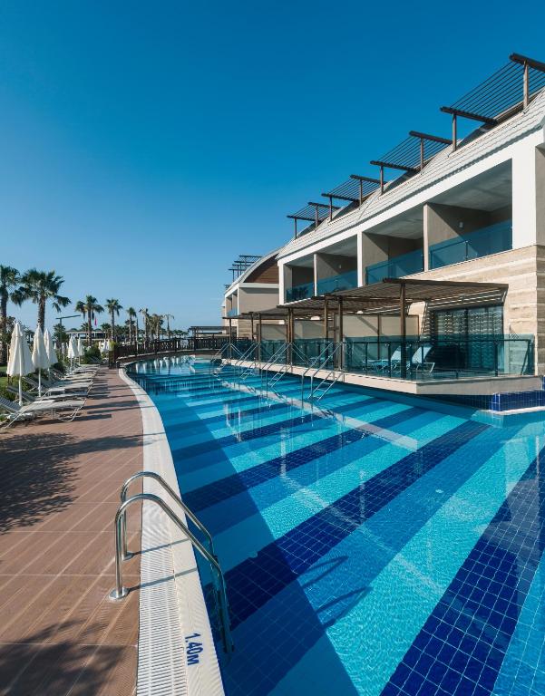 Dažādas peldbaseina zonas pie Magic Life Jacaranda ar palmām un sauļošanās krēsliem.