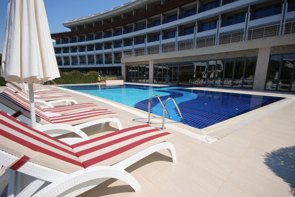 Peldbaseins un sauļošanās krēsli pie Magic Life Jacaranda.