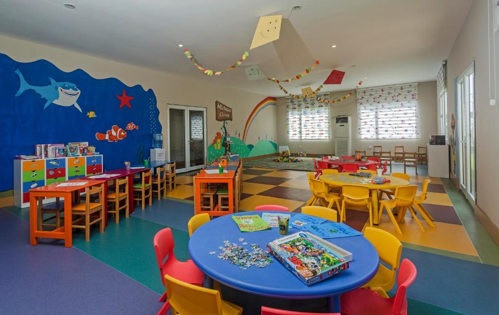 Bērnu klubs Magic Life Jacaranda ar krāsainiem galdiem un rotaļām.