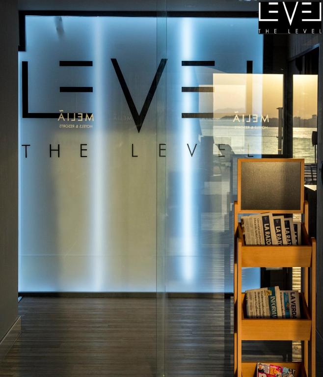 Moderns viesnīcas reģistratūras interjers ar stilīgu logo "THE LEVEL" un žurnālu stendu. Gaisma rada patīkamu atmosfēru.