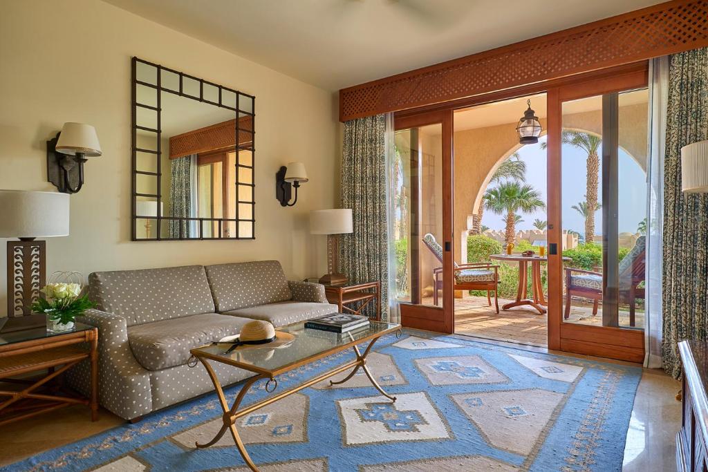 Four Seasons Resort Sharm El Sheikh numura atpūtas zona ar dīvānu un izeju uz saulainu dārza terasi.