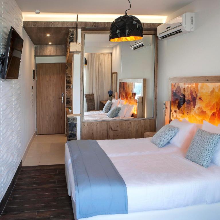 Mūsdienīgs numurs viesnīcā Elounda Orama ar ērtām gultām un dekoratīviem akcentiem.