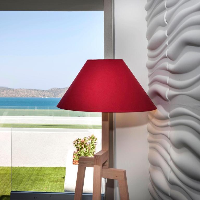 Sarkans lampas stends pie Elounda Orama ar skatu uz piekrasti.