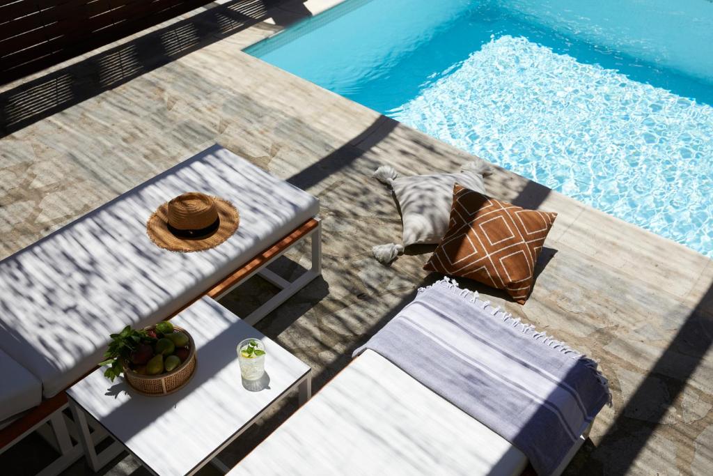 Mūsdienīgs atpūtas stūris pie baseina ar guļamo atzveltni, saules cepuri, spilveniem un dzērienu. Ideāla vieta relaksācijai un atpūtai.