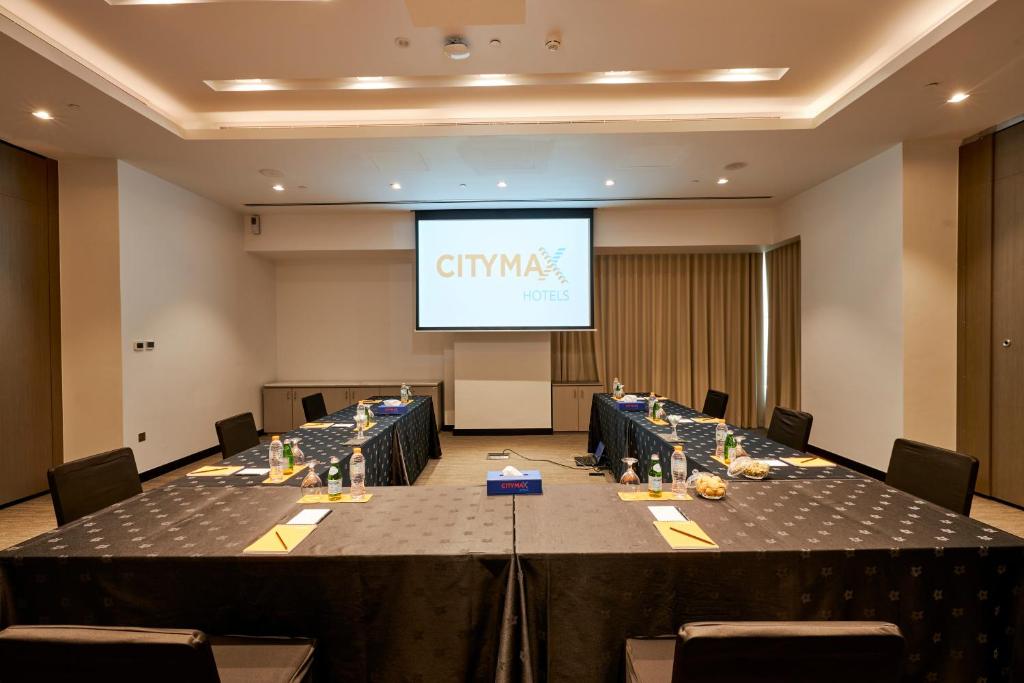 Konferenču telpa Citymax Business Bay viesnīcā ar galdiem un ekrānu.