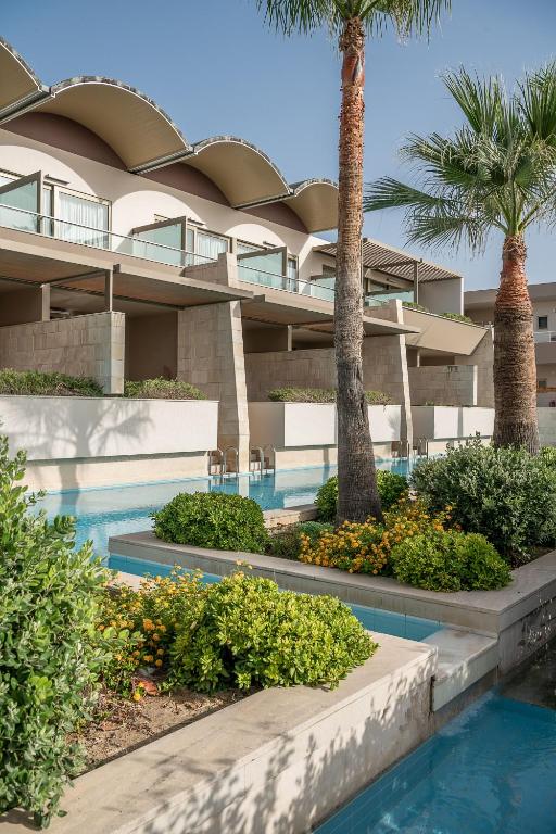 Mūsdienīgs viesnīcas komplekss ar elegantiem terases dzīvokļiem, apzaļumotu dārzu un zilu baseinu, kas rada relaksējošu atmosfēru. Ideāls galamērķis atpūtai un komfortam.