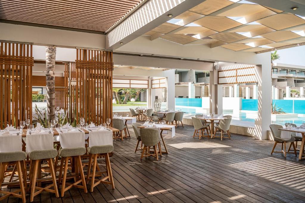 Moderns restorāns ar koka terasi un baseinu, kurā ir eleganti galdi un krēsli. Gaisīga atmosfēra un stilīgs interjers piedāvā patīkamu ēšanas pieredzi.