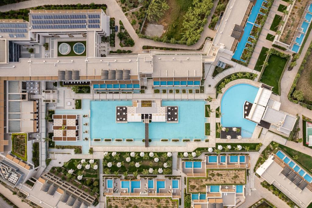 Mūsdienīgas viesnīcas komplekss ar plašiem peldbaseiniem un zaļām teritorijām, redzams no putna lidojuma. Peldbaseini un atpūtas zonas ir harmoniski izvietotas, veidojot relaksējošu atmosfēru.