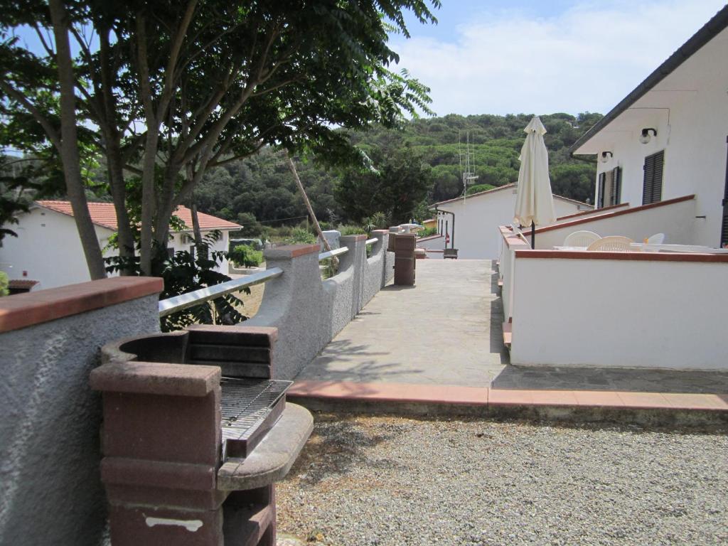 Atpūtas zona ar terasēm un grila iekārtu, ko ieskauj koki un ainava. Ideāla vieta relaksācijai un brīvā laika pavadīšanai.