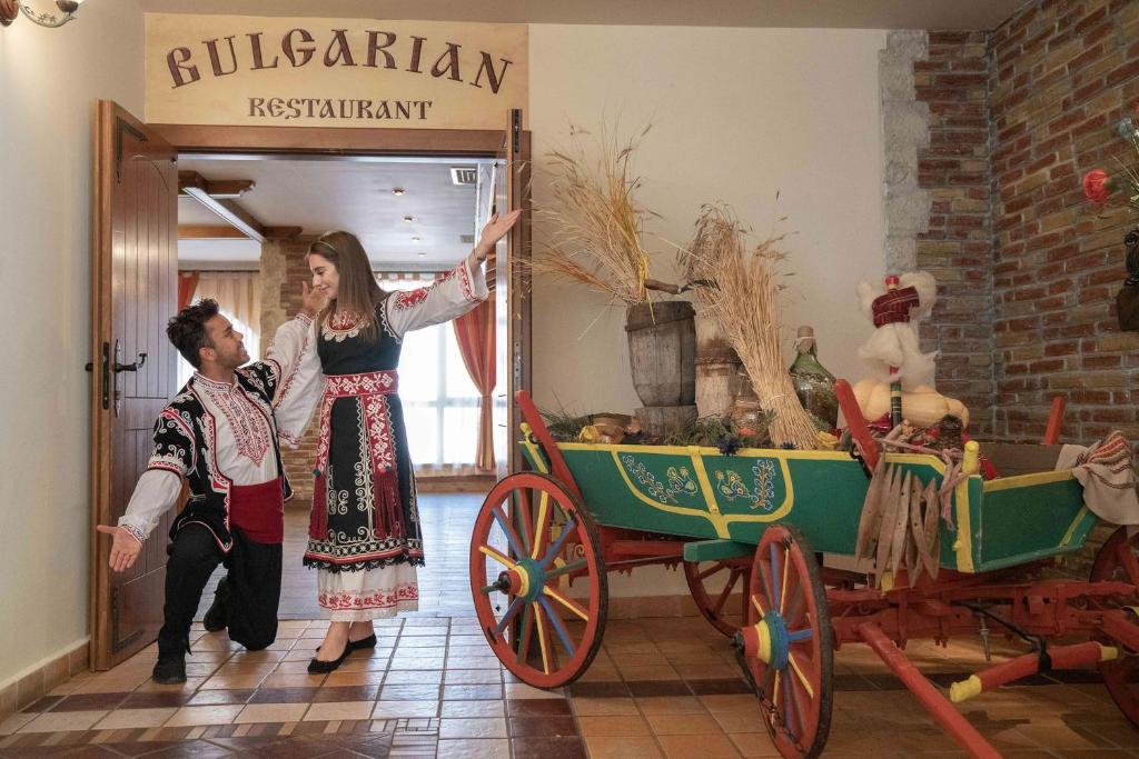 Tradicionāls bulgāru restorāns ar diviem dejotājiem, tērpti tradicionālās kāzās, un krāsainu ratiņu dekoru. Atmosfēra ir silta un viesmīlīga, atspoguļojot bulgāru kultūru.