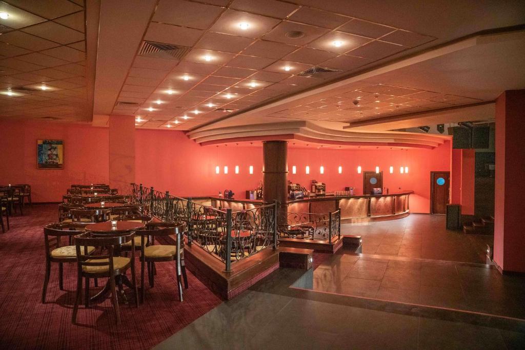 Elegantā restorāna interjers ar siltām rozā sienām un mīkstu apgaismojumu, piedāvājot galdiņus un krēslus. Bāra zona ir izcelta, radot patīkamu atmosfēru.