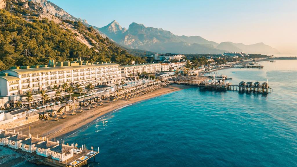 Corendon Playa Kemer viesnīca ar pludmali piekrastē un kalniem fona