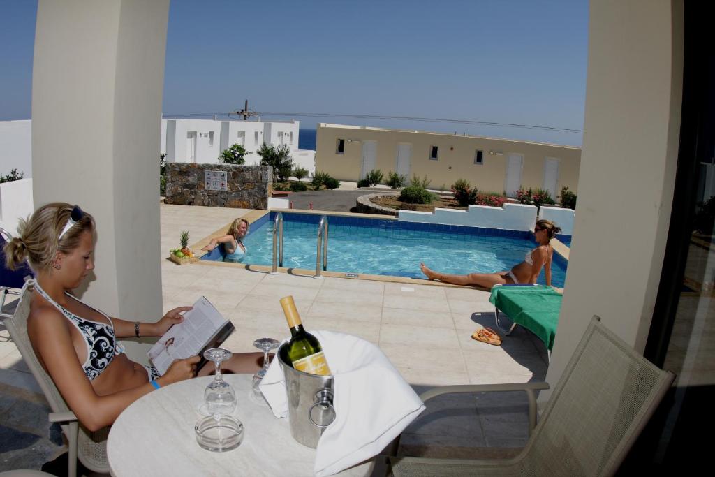 Divas sievietes atpūšas pie Mediterraneo Hotel baseina, viena lasa grāmatu.