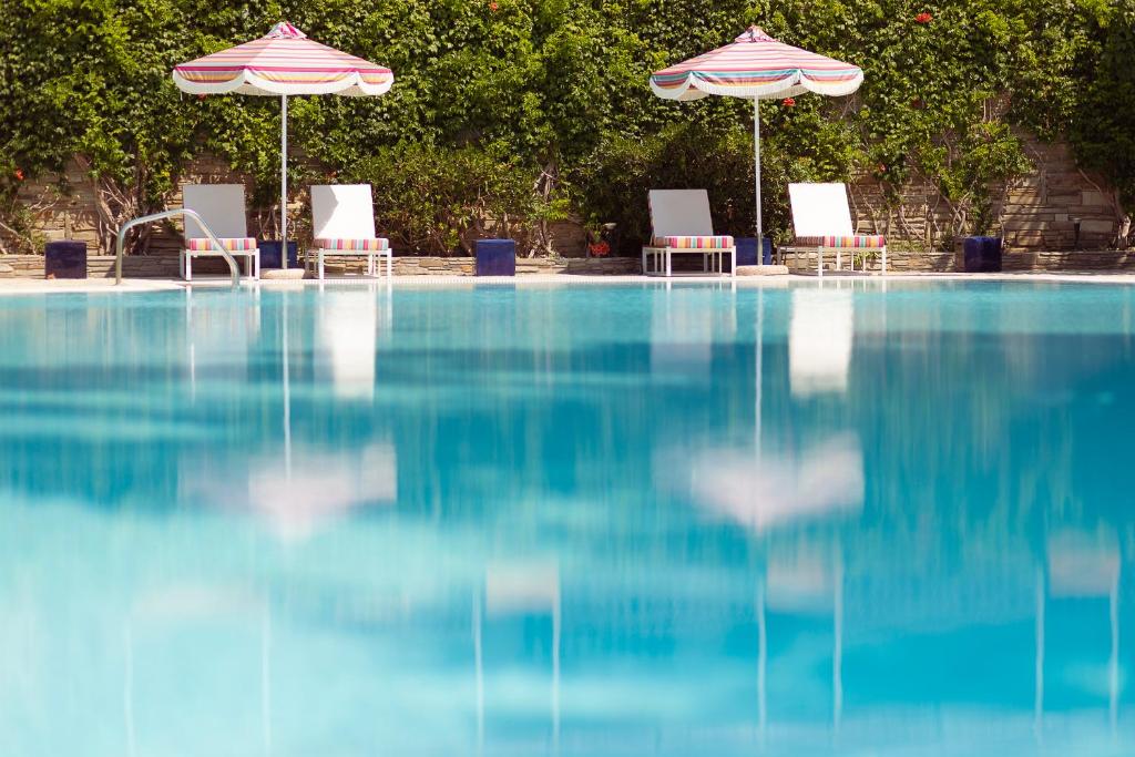 Baseins ar skaidru ūdeni, blakus saulessargi un atpūtas krēsli, ieskauti zaļiem krūmiem. Ideāla vieta relaksācijai un atpūtai.