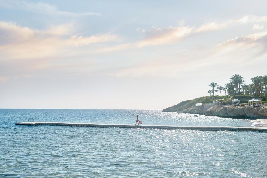 Four Seasons Resort Sharm El Sheikh mols saulrietā ar pastaigājošos viesi.