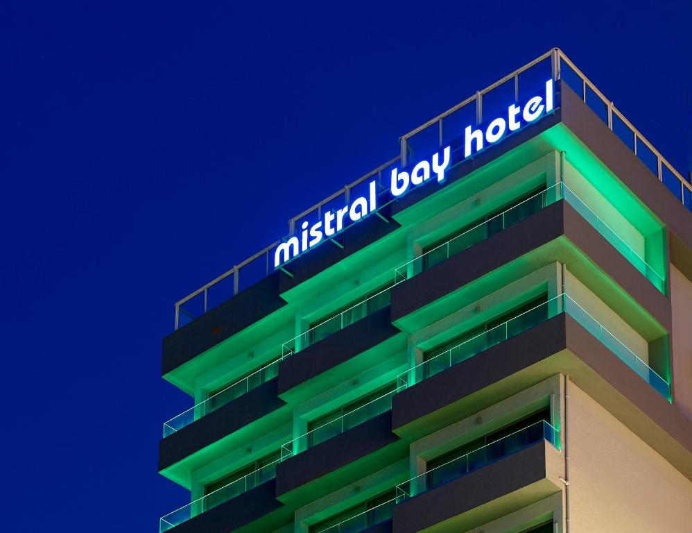 Mistral Bay Hotel apgaismota piekrastē vakarā.