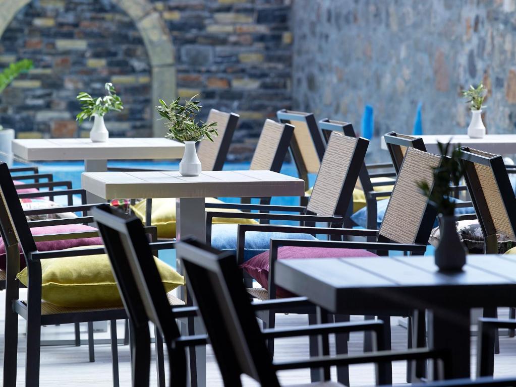 Mistral Bay Hotel terase ar krāsainām spilveniem un zālēm uz galdiem.
