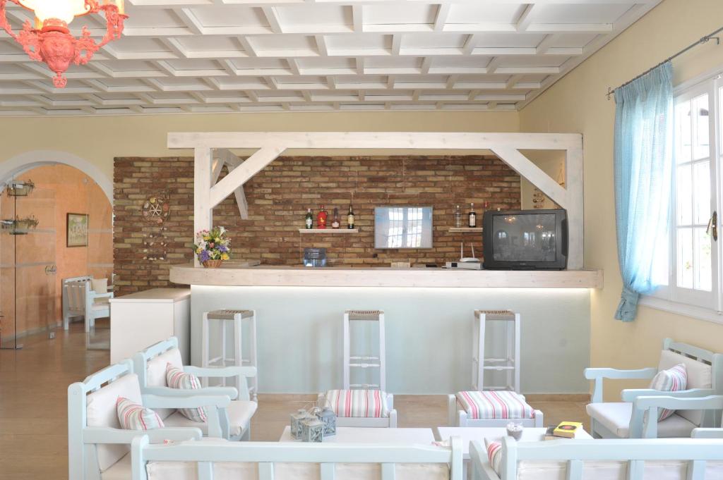 Mūsdienīga viesnīcas bāra zona ar siltām krāsām, akmens sienu un baltu koka konstrukciju, kas rada relaksējošu atmosfēru. Sēdvietas ar spilveniem un plāna gaisma papildina interjeru.