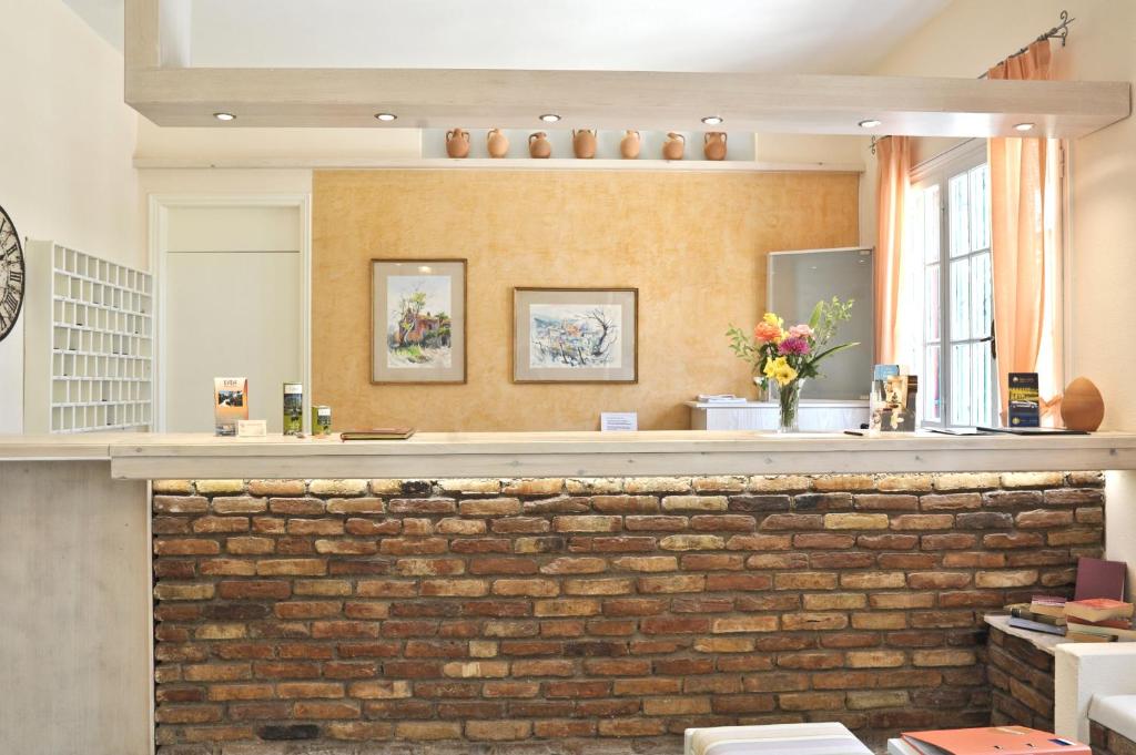 Recepcija ar siltu un viesmīlīgu atmosfēru, akmens mūris un mākslas darbi uz sienas. Uz galda ziedu kompozīcija un informatīvie materiāli.