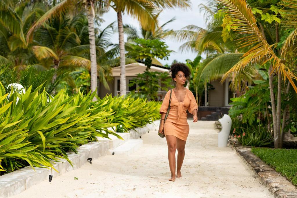 Mwezi Boutique Resort tropisks dārzs ar sievieti pastaigā.