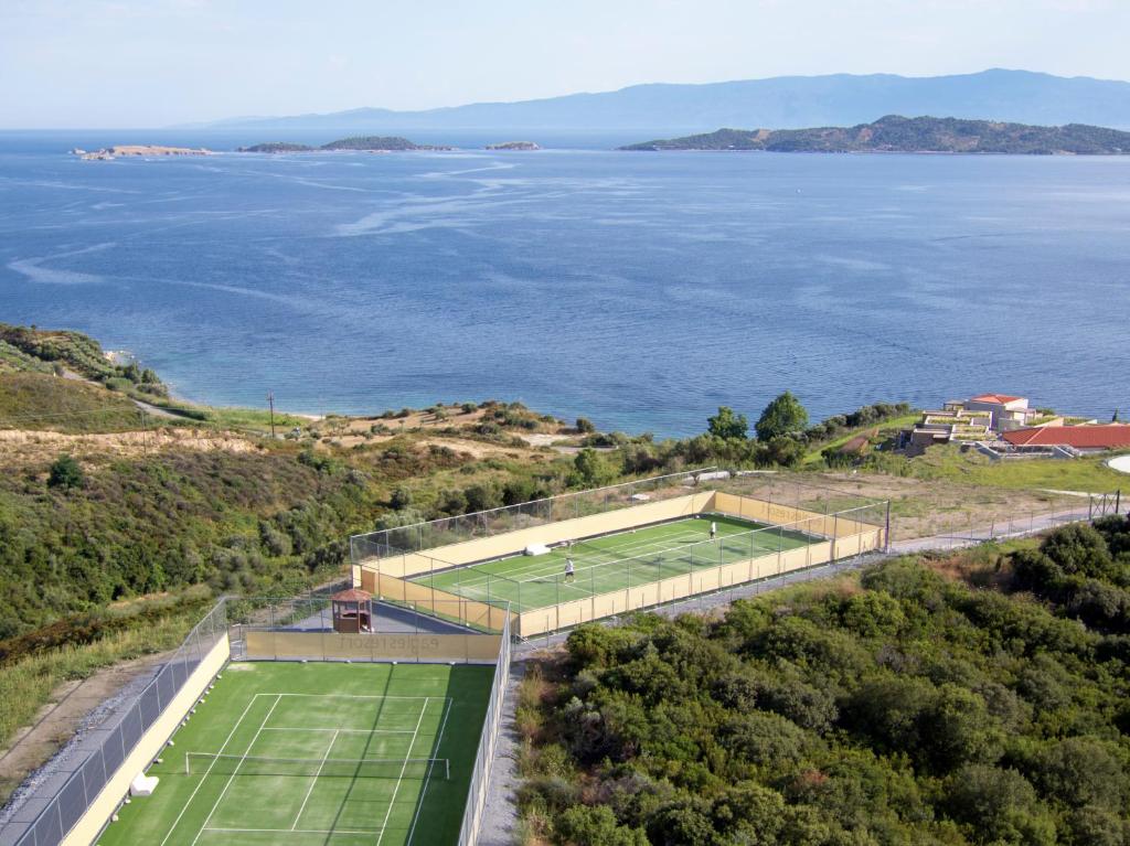 Skats uz diviem tenisa laukumiem kalnu piekrastē, fonā redzams jūra un salas. Ideāla vieta sportam un atpūtai.