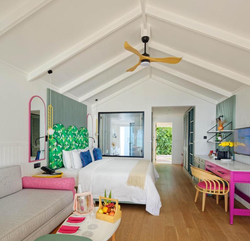 Mūsdienīgs viesnīcas numurs ar gaišu interjeru, kas ietver zaļus akcentus un krāsainu mēbelējumu. Numurā ir liela gulta, dīvāns un galda zona ar augļu grozu.