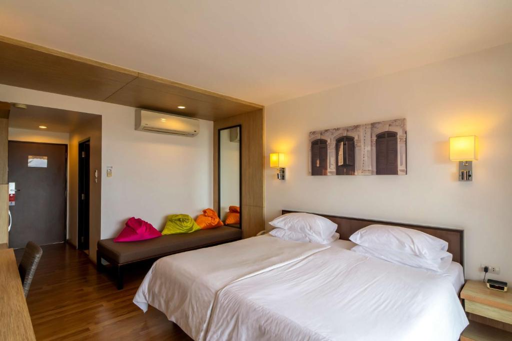 Mūsdienīgs viesnīcas numurs ar divām gultām, koka grīdu un spilgtiem spilveniem. Interjerā ir gaismas ķermeņi un sienas māksla ar pilsētas skatu.