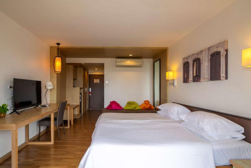 Mūsdienīgs viesnīcas numurs ar divām gultām, televizoru un ērtu darba vietu. Telpā ir gaiša apgaismojums un krāsaini sēdvietas, kas veido patīkamu atmosfēru.