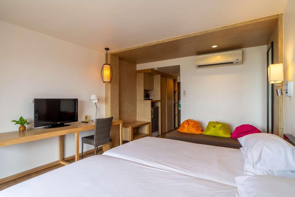 Mūsdienīgs viesnīcas numurs ar divām gultām, televizoru un darba stūri, kā arī krāsainiem spilveniem atpūtas zonā. Interjers ir gaišs un elegants, nodrošinot komfortablu atmosfēru.