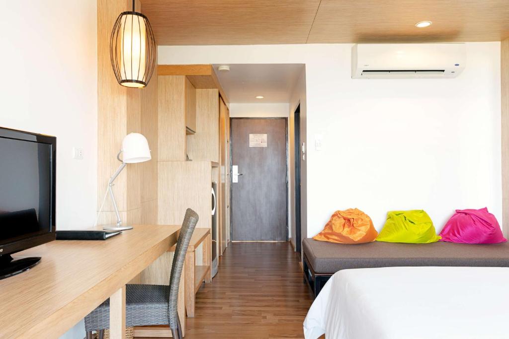 Mūsdienīga viesnīcas numura interjers ar koka grīdu, televizoru un rakstāmgaldu, kā arī spilgti krāsainām piepūšamām sēdvietām. Gaismas un telpas dizains rada komfortablu un relaksējošu atmosfēru.