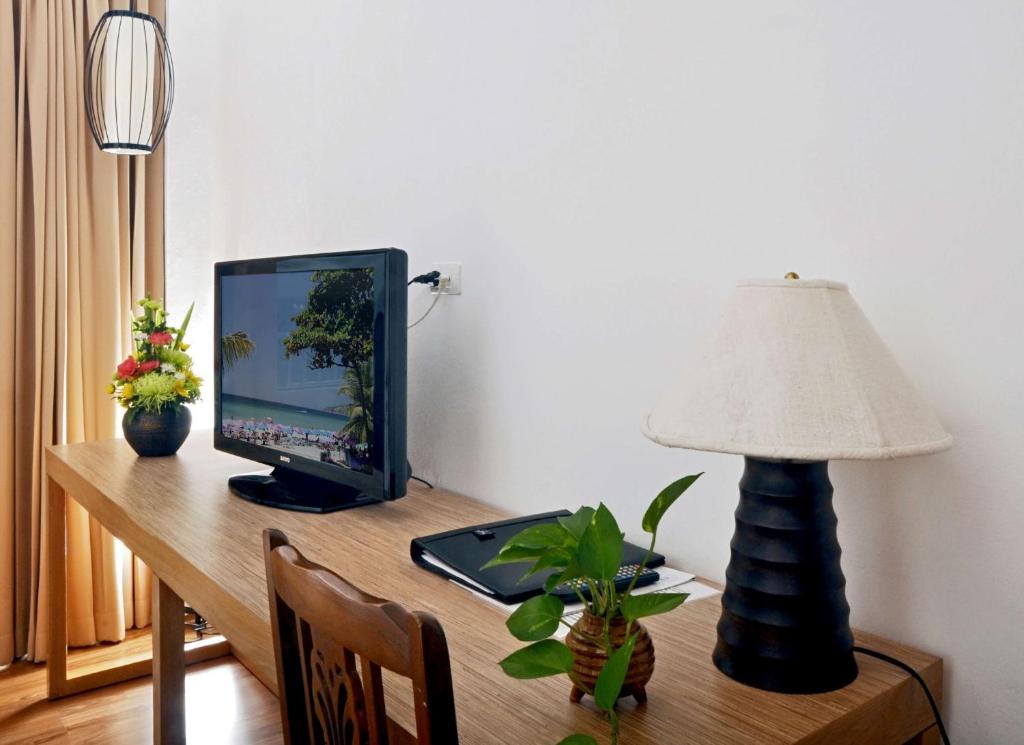 Moderna un eleganta galda zona ar televizoru, lampu un dekoratīvu ziedu kompozīciju. Iekārtojums veido komfortablu un stilīgu atmosfēru.