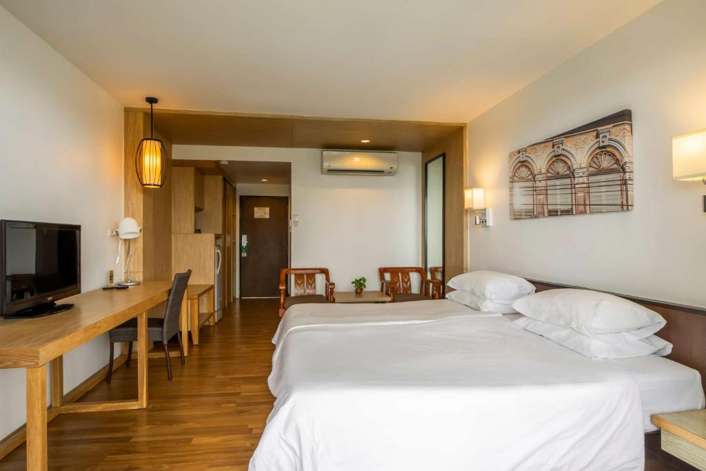 Mūsdienīgs viesnīcas numurs ar diviem gultasveļas komplektiem, koka grīdu un ērtu darba zonu. Interjers ir gaišs un gaumīgs, ar televizoru un dekoratīvu mākslas darbu uz sienas.