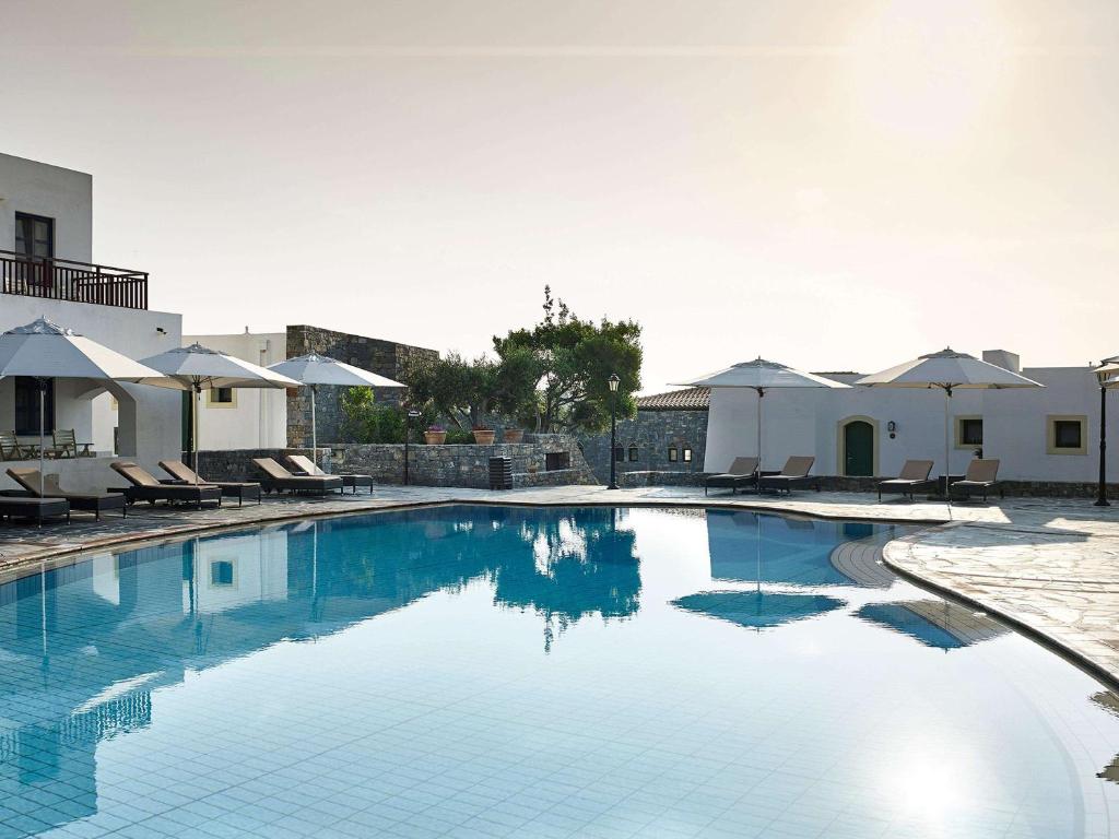 Creta Maris Resort baseins ar saulessargiem un atpūtas krēsliem piekrastē