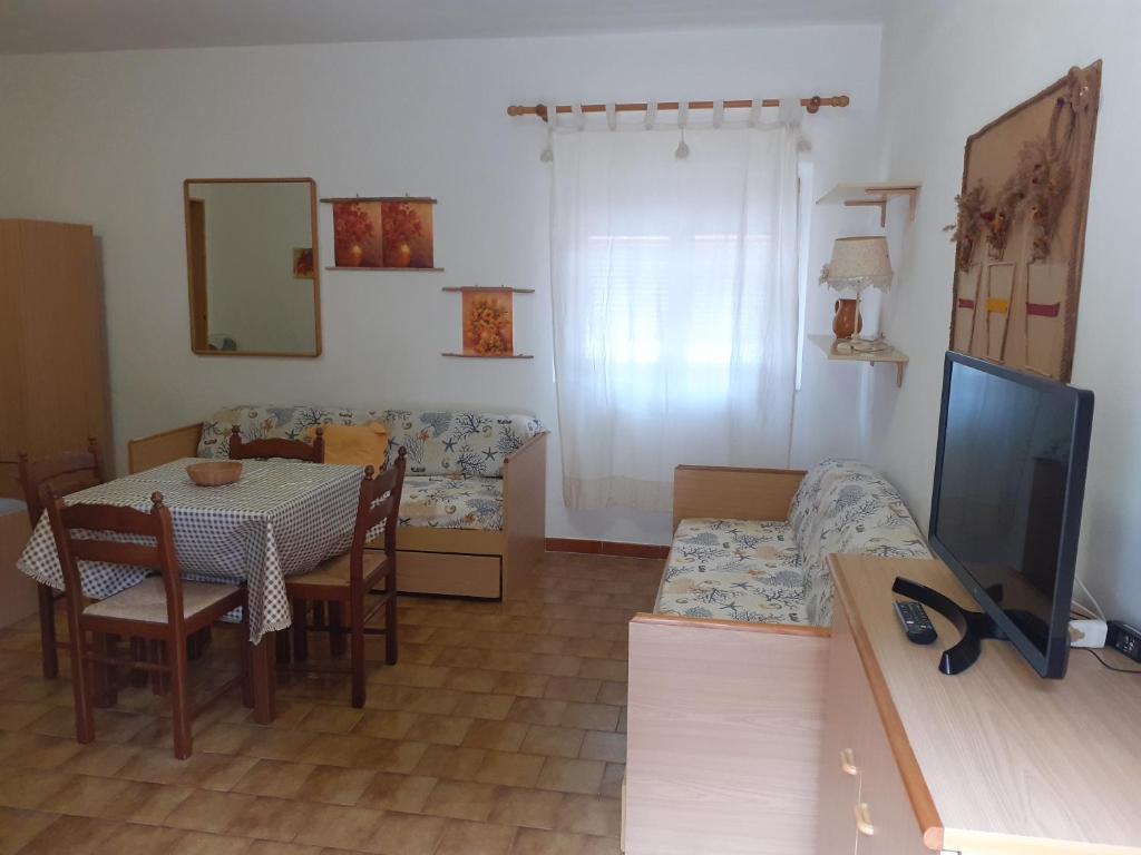 Mājīgs viesistaba ar ēdamgaldu un divām dīvāngultām, dekorēta ar gaismu un dabīgiem toņiem. Telpā ir televizors un liels logs, kas nodrošina dabisko apgaismojumu.