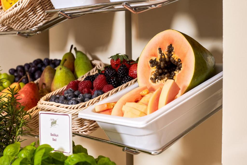 Svaigi augļi un dārzeņi, tostarp papaja un ogas, sakārtoti grozos un traukos, radot veselīgu un pievilcīgu izskatu.