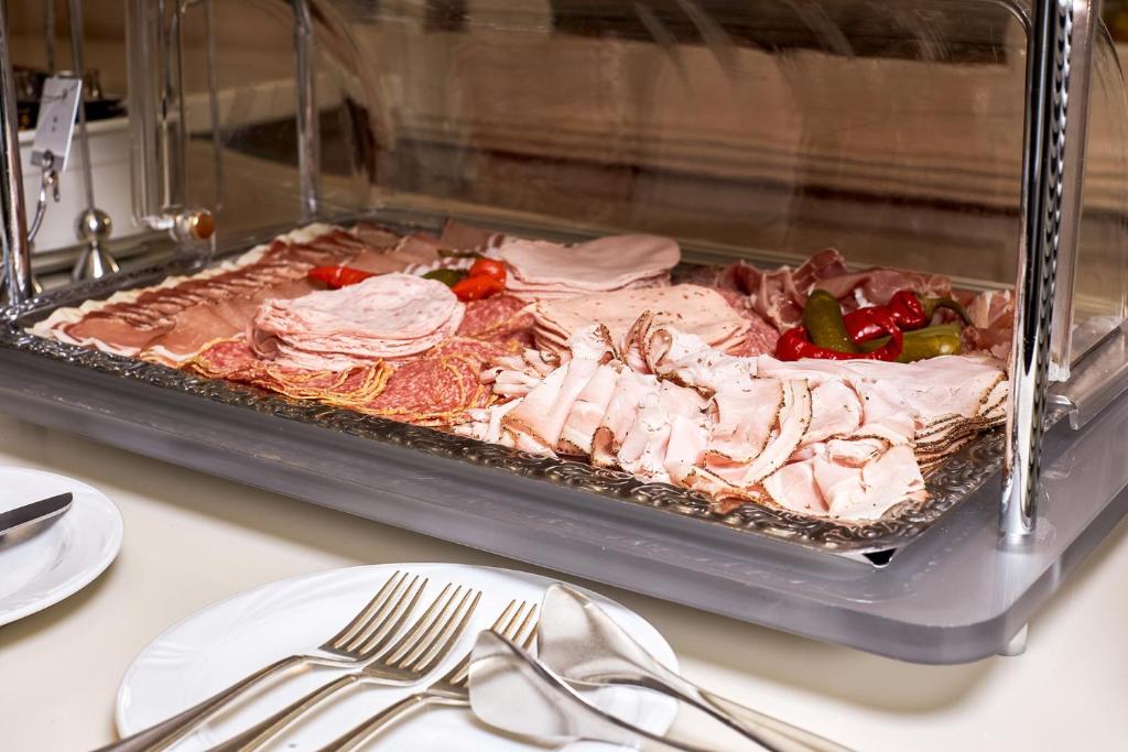 Sviestā un gaļas šķēles, kas pasniegtas uz bufetes galda ar marinētiem dārzeņiem. Ideāla izvēle brokastīm vai uzkodām.