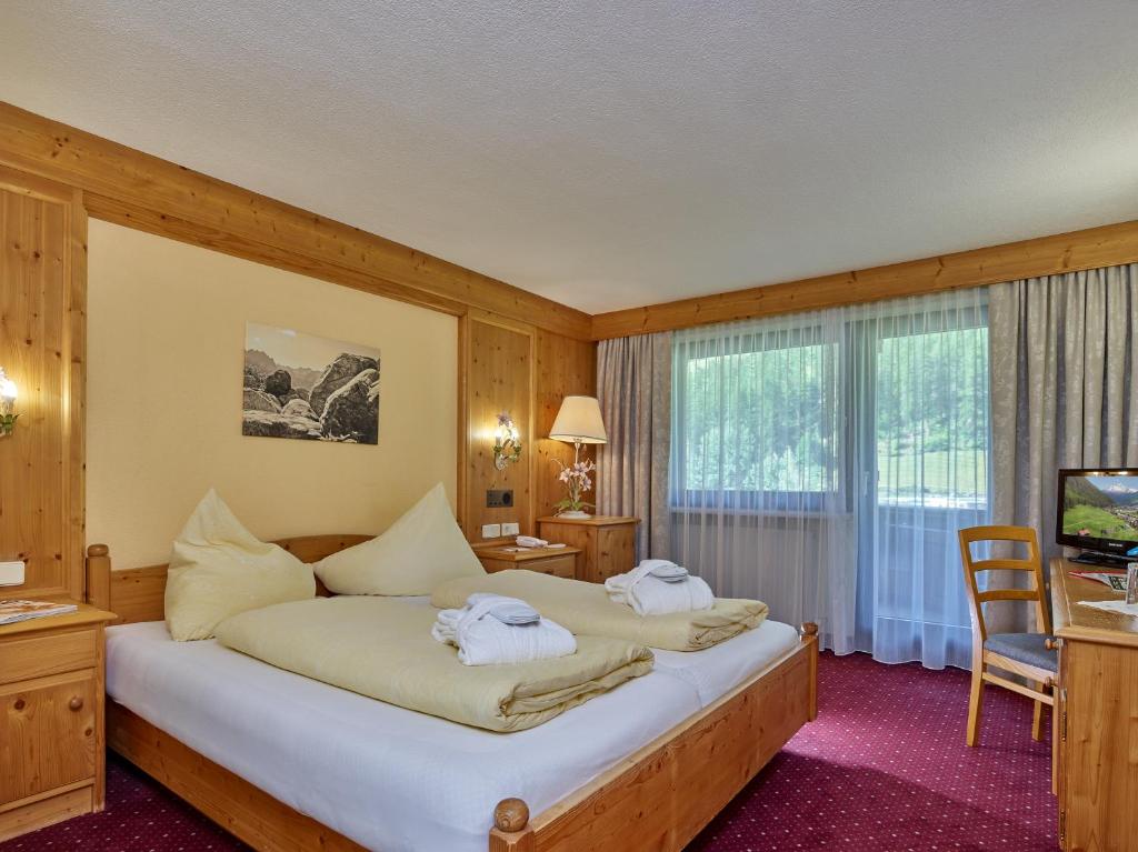 Mūsdienīgs viesnīcas numurs ar koka apdari, divām gultām un dīvānu, kas piedāvā komfortu un mierīgu atmosfēru. Logi nodrošina dabisko apgaismojumu un skatu uz apkārtni.