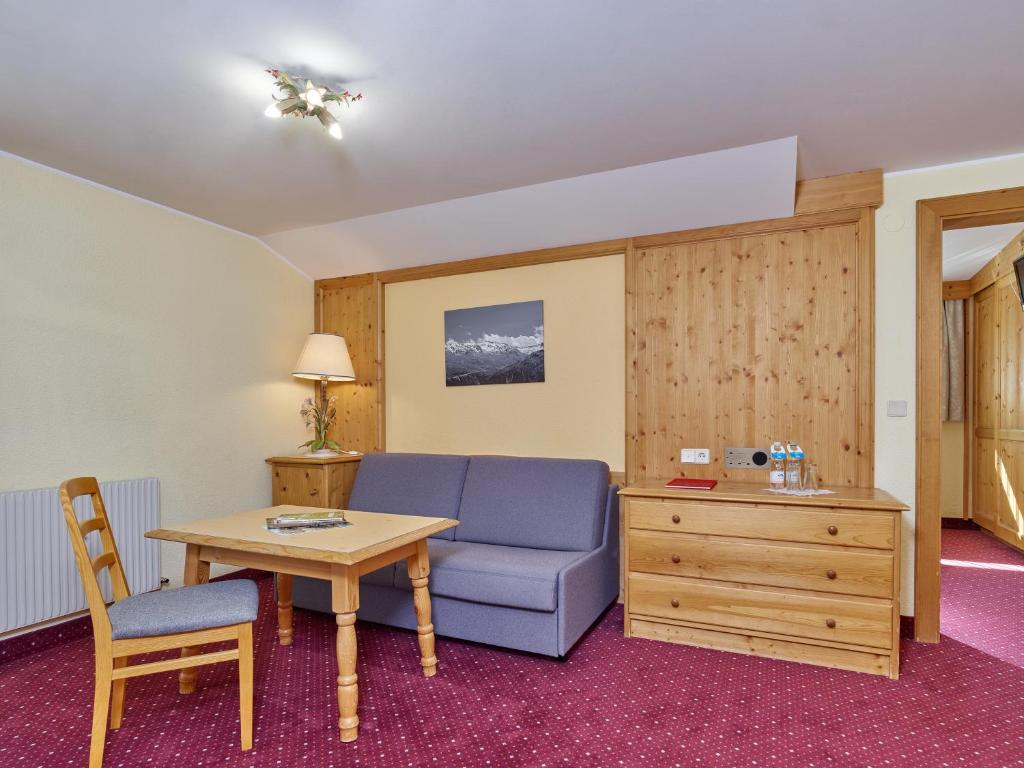 Mūsdienīgs viesnīcas numurs ar koka apdari, ērtu dīvānu un galdu, kas ideāli piemērots atpūtai. Telpā ir arī televizors un gaismas avots, radot mājīgu atmosfēru.