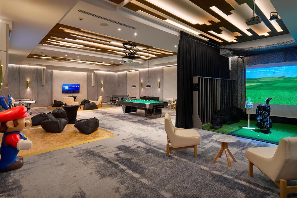Mūsdienīga izklaides telpa ar biljarda galdu, golfa simulatoru un komfortablām sēdvietām, kurā redzams spēļu varonis.