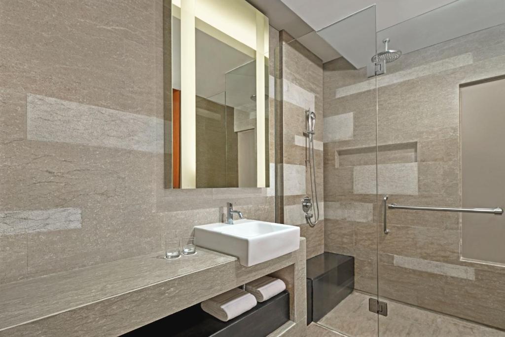 Mūsdienīgs vannas istabas interjers ar akmens apdari, stikla dušu un elegantu izlietni. Ideāls dizains, lai radītu relaksējošu atmosfēru.