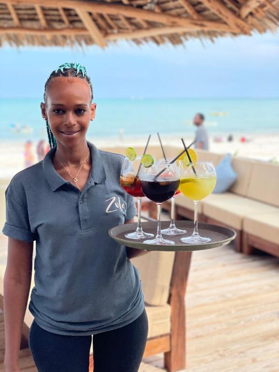 Zula Zanzibar darbiniece ar dzērieniem pie pludmales.