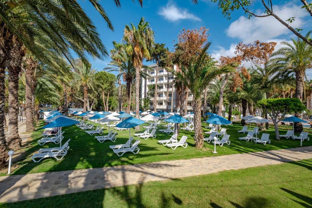 Utopia Resort & Residence atpūtas zona ar palmu kokiem un sauļošanās krēsliem piekrastē.