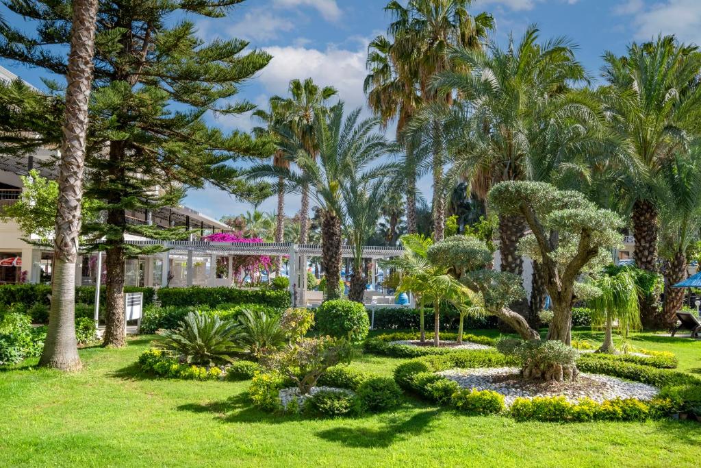 Utopia Resort & Residence greznā dārza ainava ar palmu un ziedu kompozīcijām.