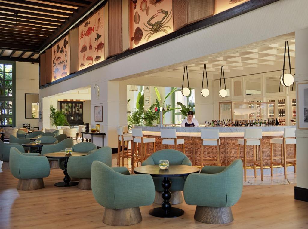 Mūsdienīgs restorāns ar elegantiem zaļiem krēsliem un plašu bāru, kurā ir spožas gaismas un tropiskie augu akcenti. Interjerā redzami mākslas darbi, kas attēlo jūras dzīvi.